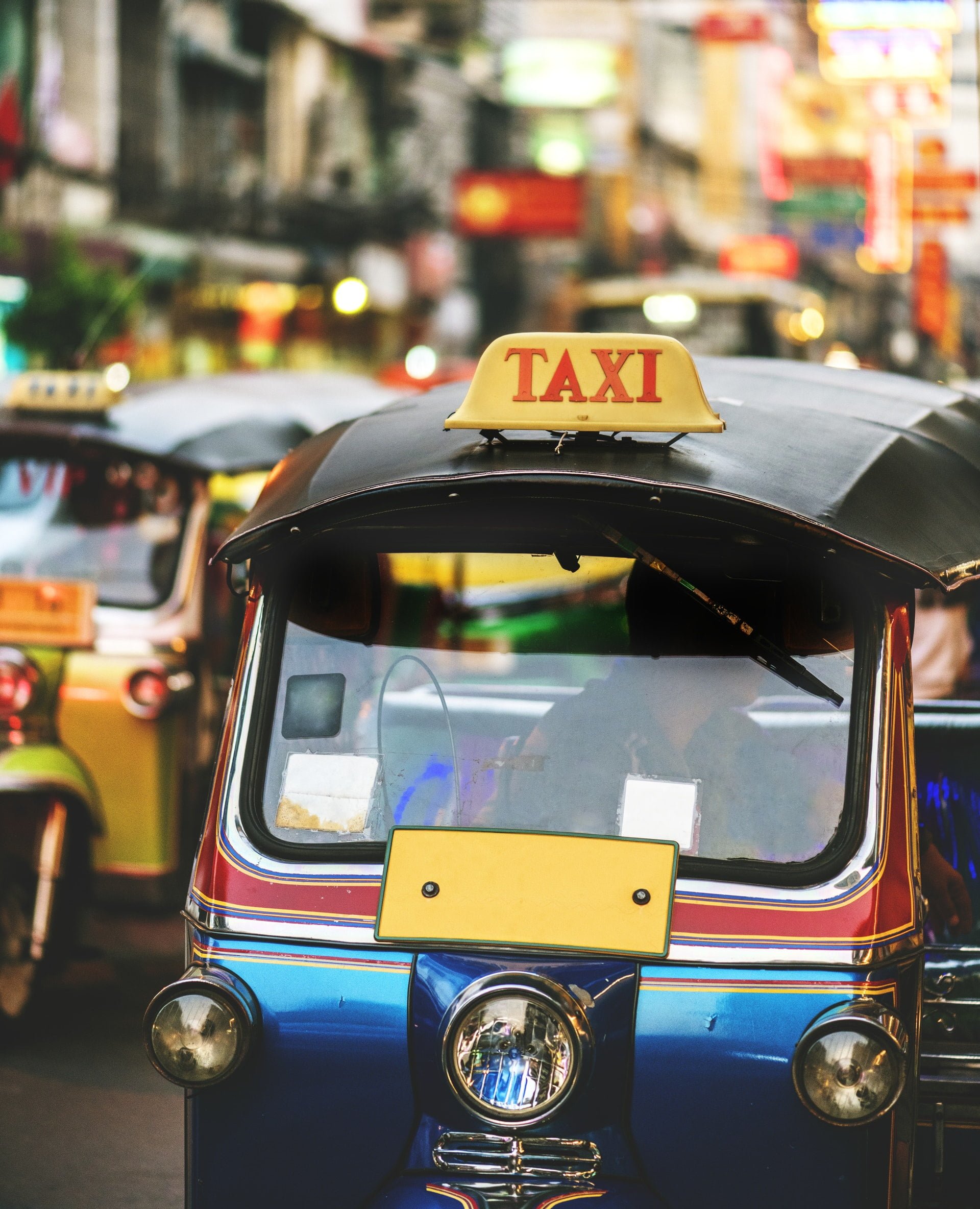 泰國旅遊一定要玩到的25種景點、美食與活動 two blue and yellow auto rickshaws on road Thailand Bangkok